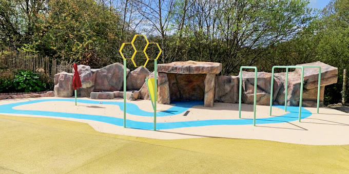 Aire de jeux aquatique réalisée : structures ludiques colorées sur sol souple et rochers décoratifs