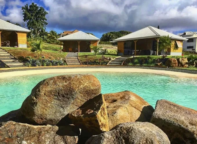 Lagon minéral réalisé : bassin turquoise bordé de rochers paysagers, plage de sable et bungalows
